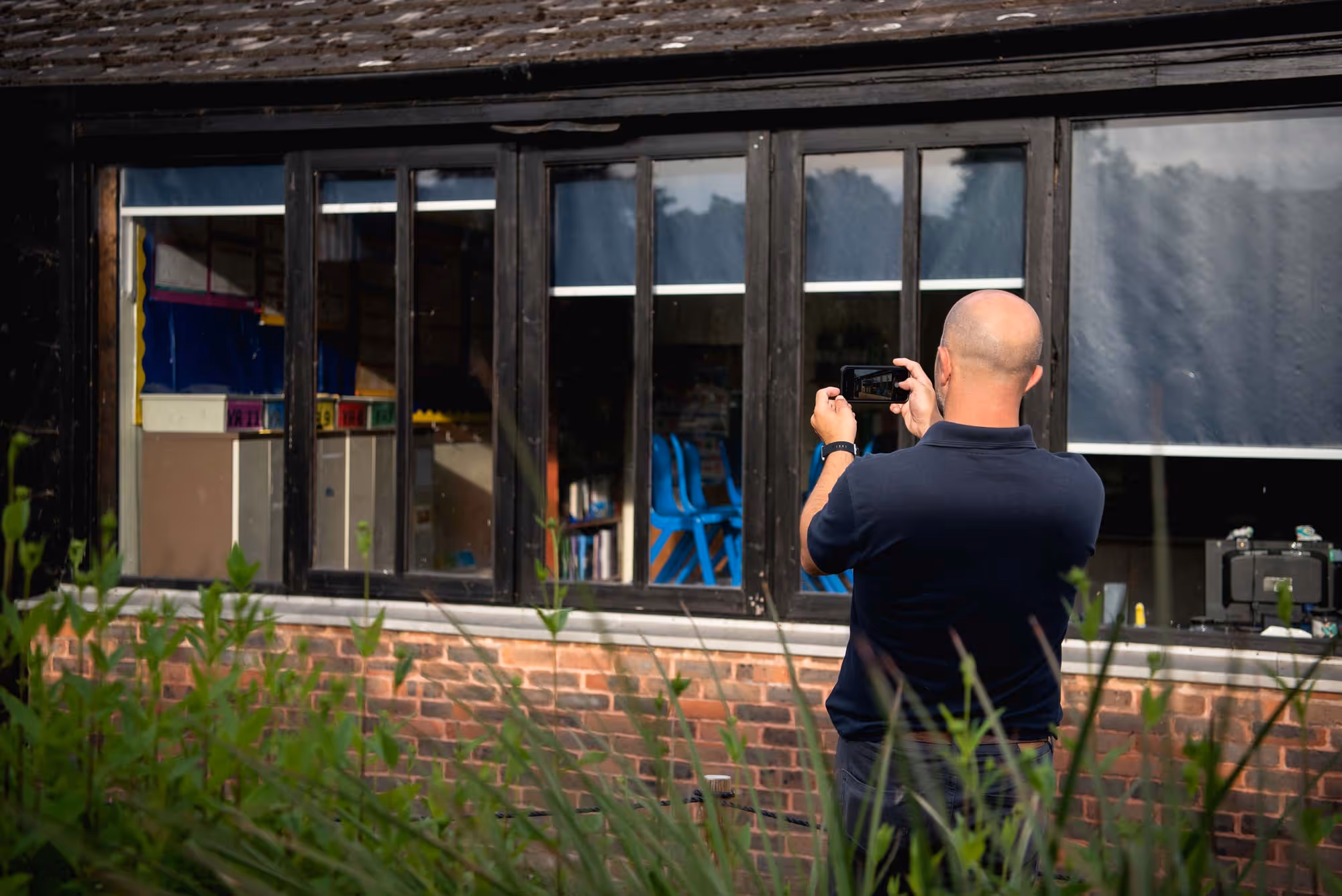 A person takes a photo of a reflection in a large window.