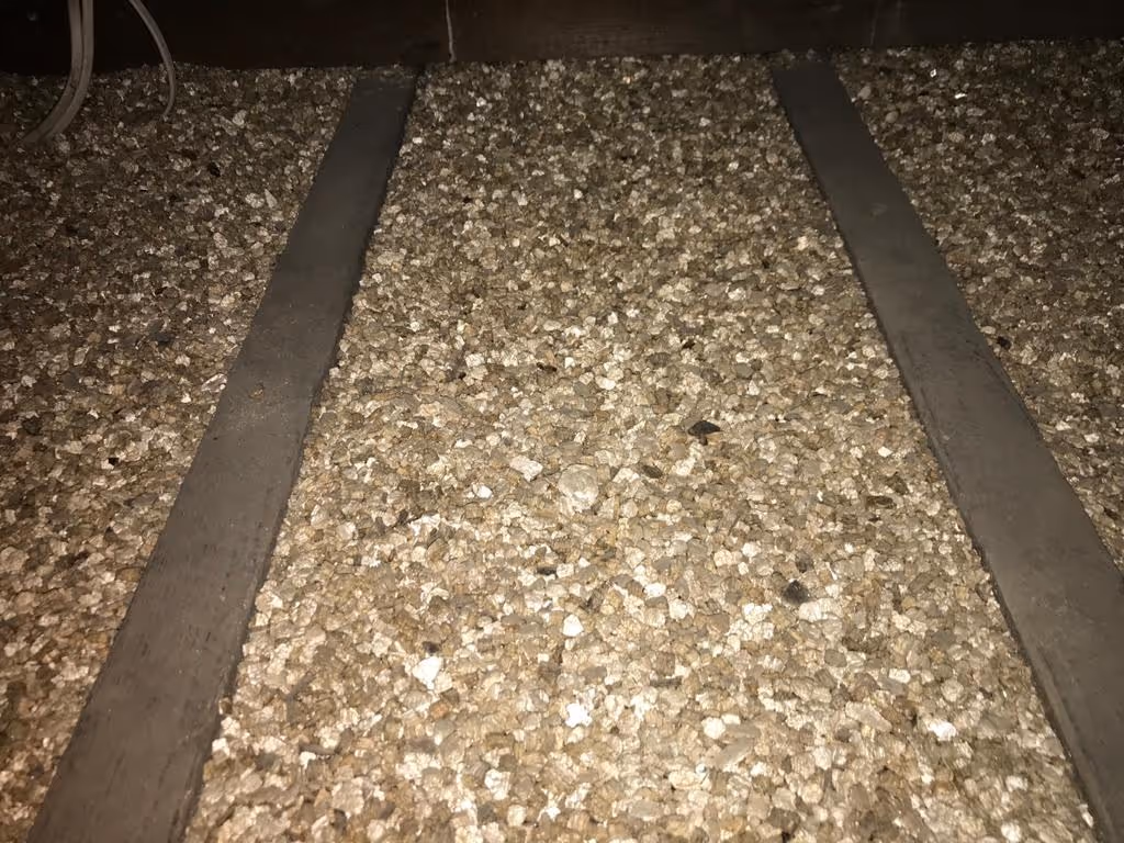 Close-up of a rough gravel surface with two parallel metal strips on top.