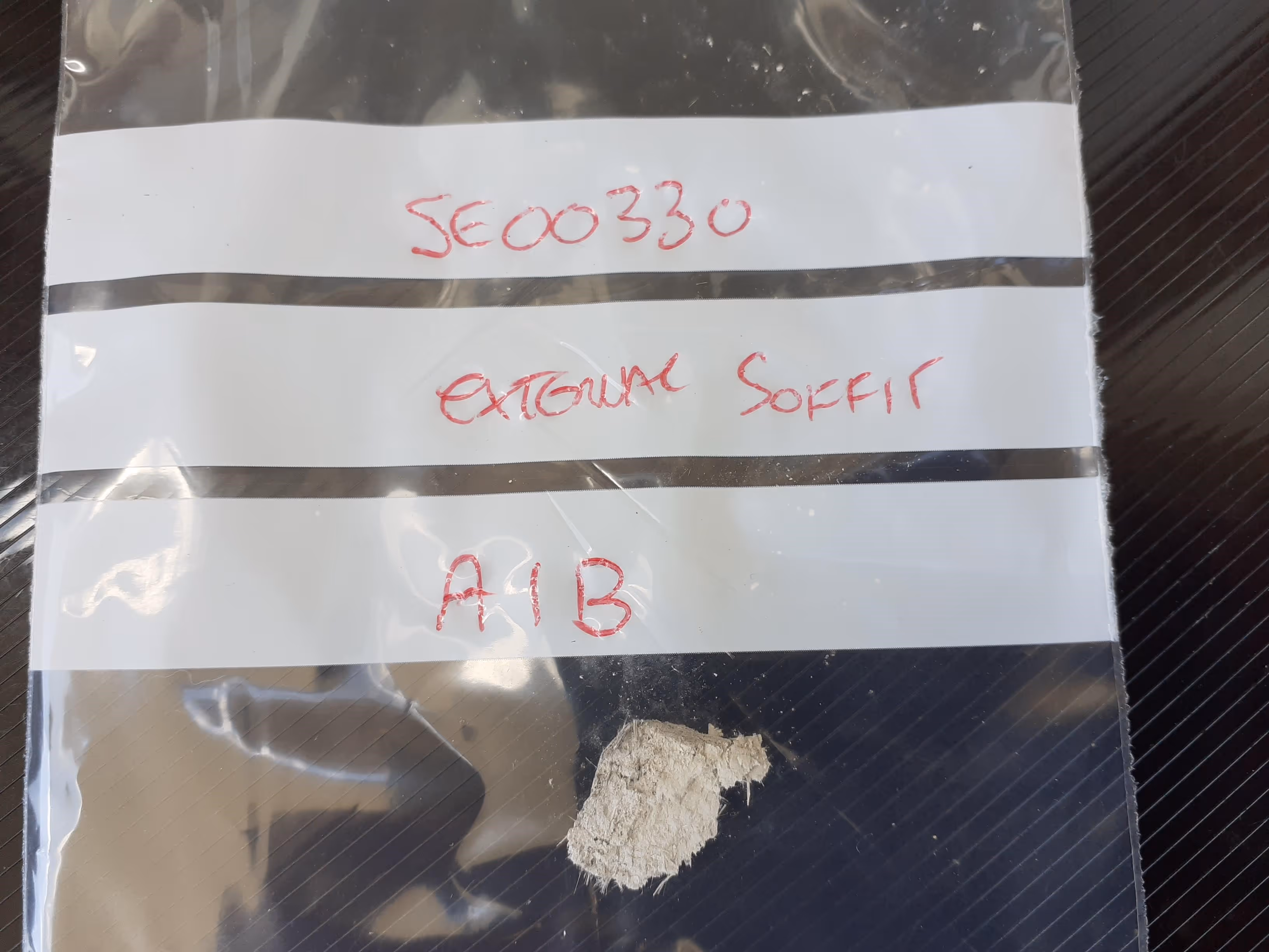 A small plastic bag contains a sample of white powder labeled with handwritten text.
