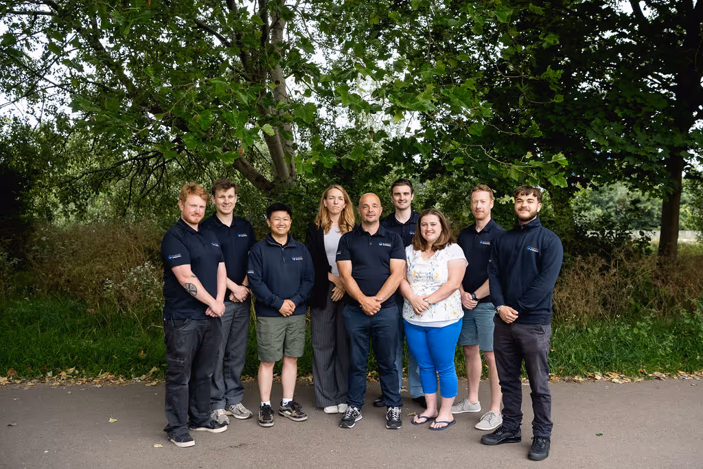 A group of nine people standing together outdoors, smiling and posing for a group photo.