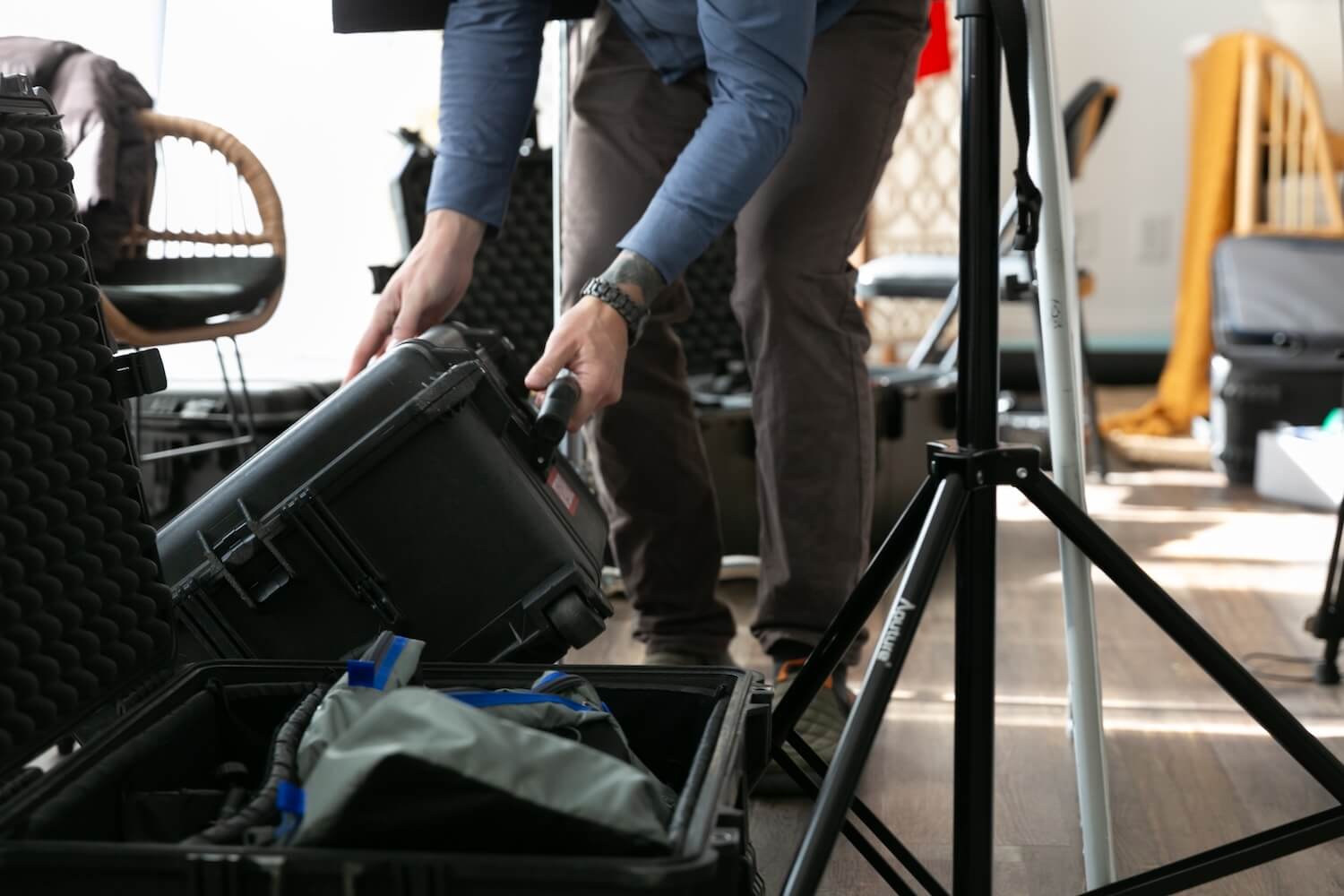 Smiling woman with long hair holding a digital tablet and stylus while sitting at a table with a dark textured wall in the background.