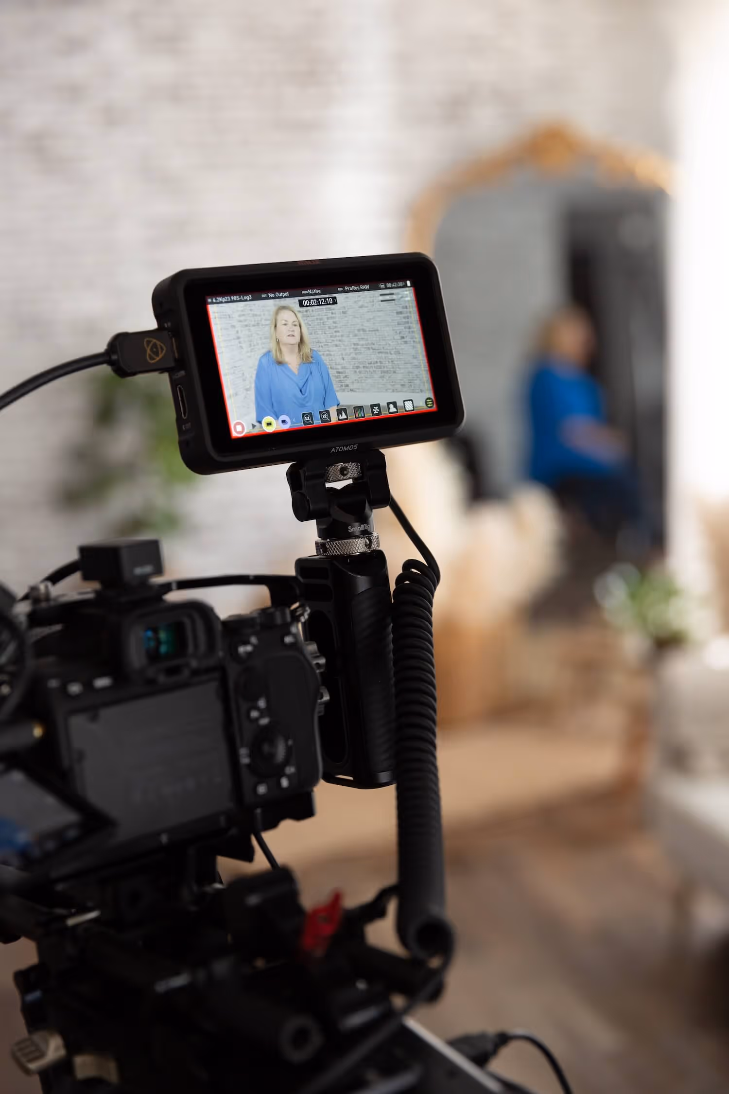 Person with curly hair and glasses editing video on a desktop computer in a cozy workspace.