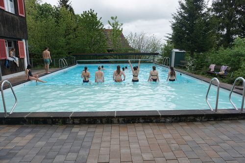 Eine Gruppe von Menschen, die in und um einen Swimmingpool herumstehen.