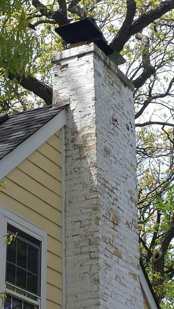 Signs that your chimney needs repaired, Spring chimney masonry deterioration on older Chicagoland home showing cracked brickwork, peeling exterior coating, and visible weather-related wear after winter exposure