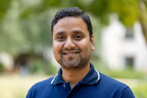 A man wearing a blue shirt and smiling.