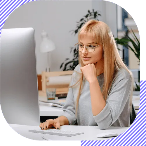 A woman with blonde hair and glasses is using a computer.