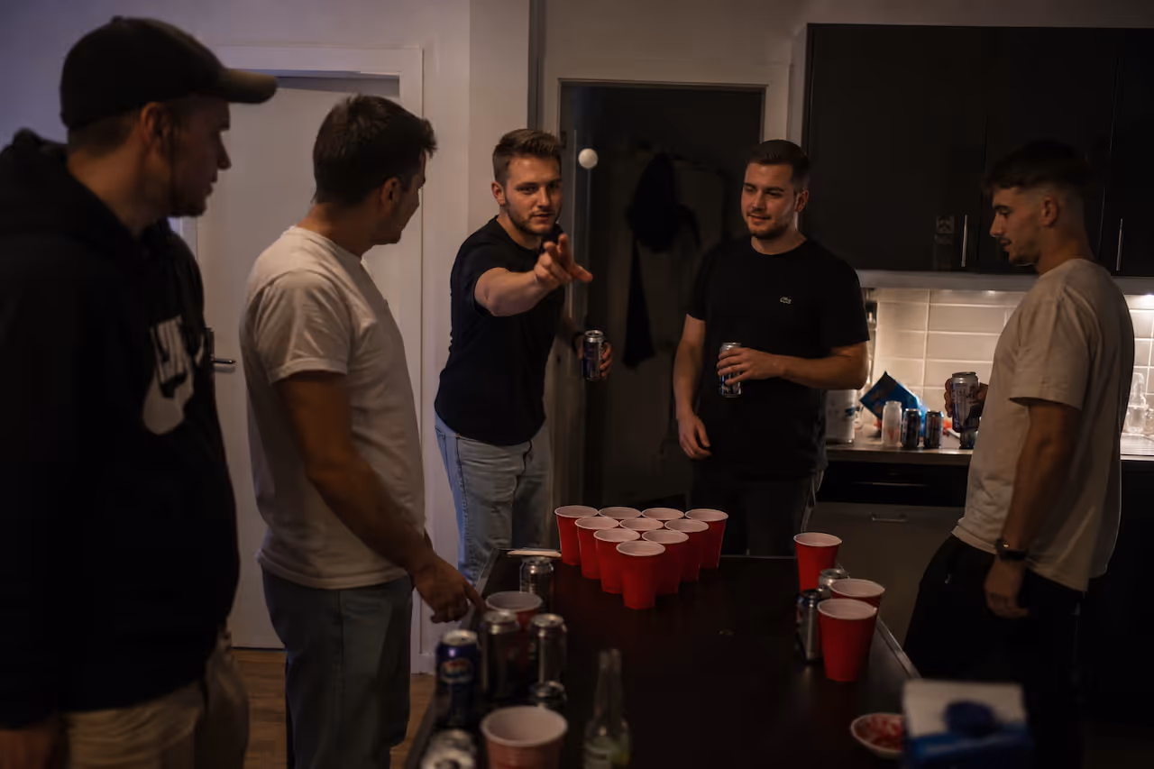 Fünf Männer spielen Bier-Pong mit roten Bechern im 7th Space
