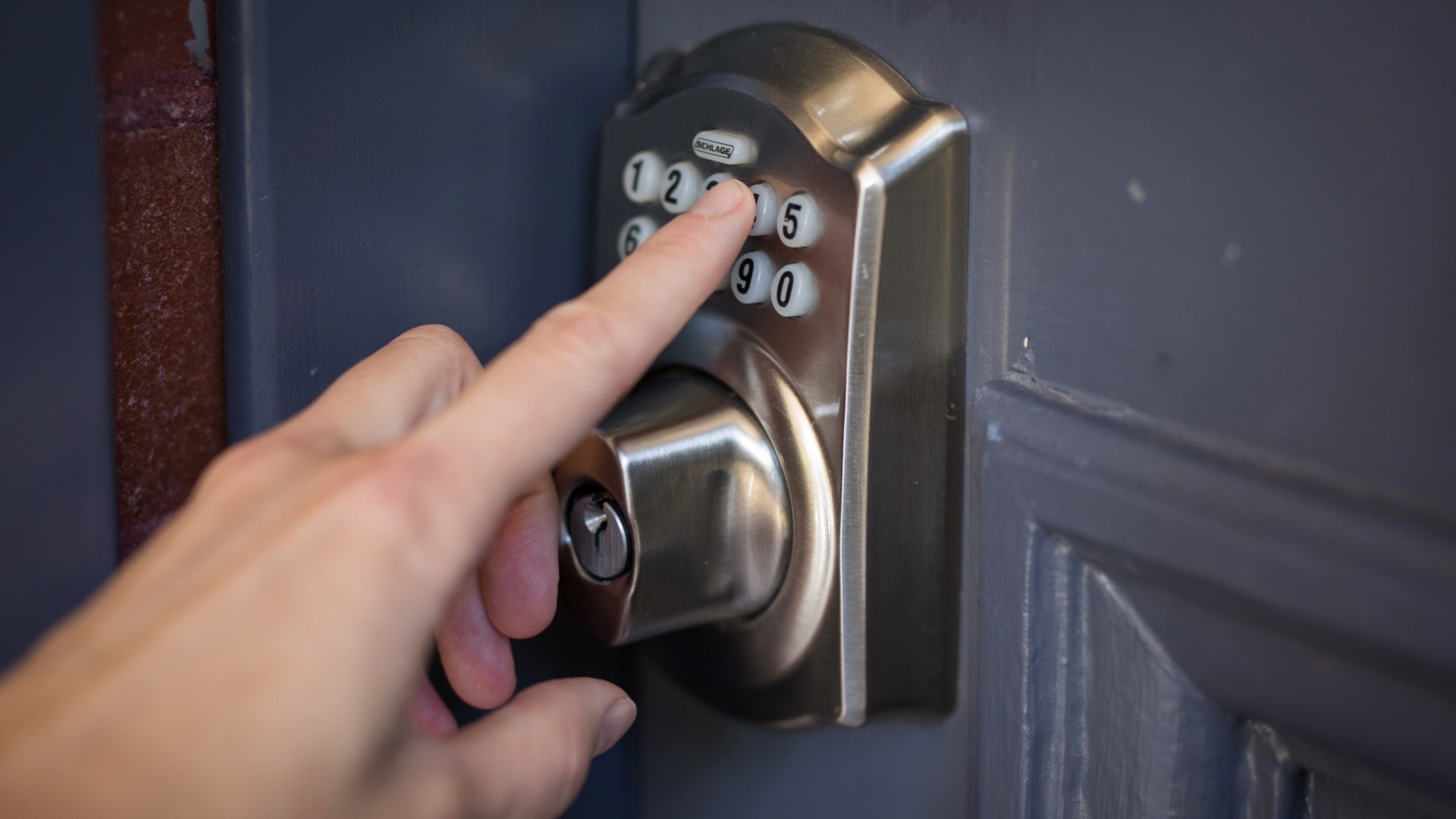 Hand pushing numbers on keypad combination door lock for Airbnb