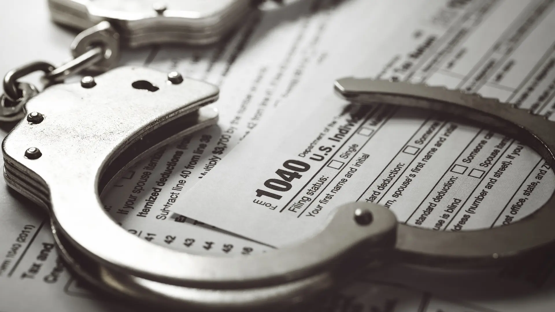 Handcuffs resting on a U.S. 1040 tax form, symbolizing tax identity theft and fraudulent tax filings