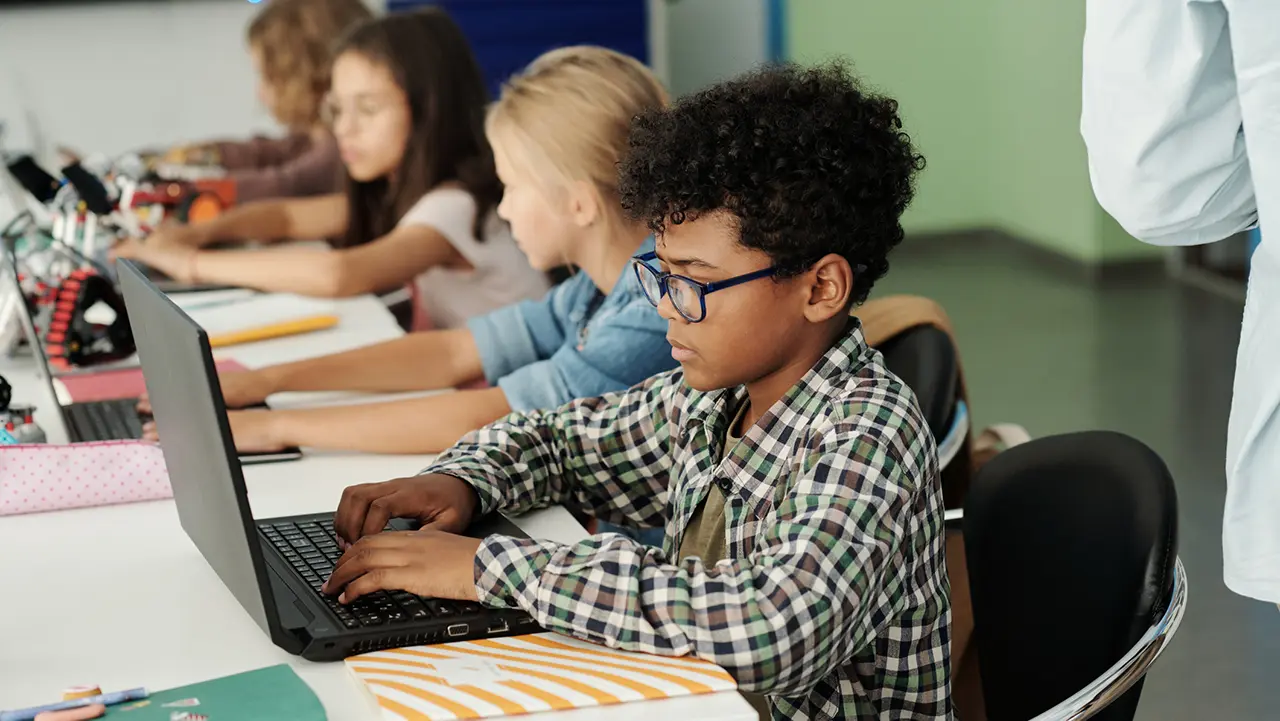 Students working on laptops in a classroom, representing K through 12 students whose data may have been exposed in the Canvas data breach 2026.