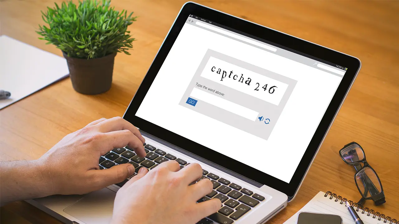 Person using a laptop displaying a CAPTCHA verification screen related to a fake CAPTCHA scam and online security threats.
