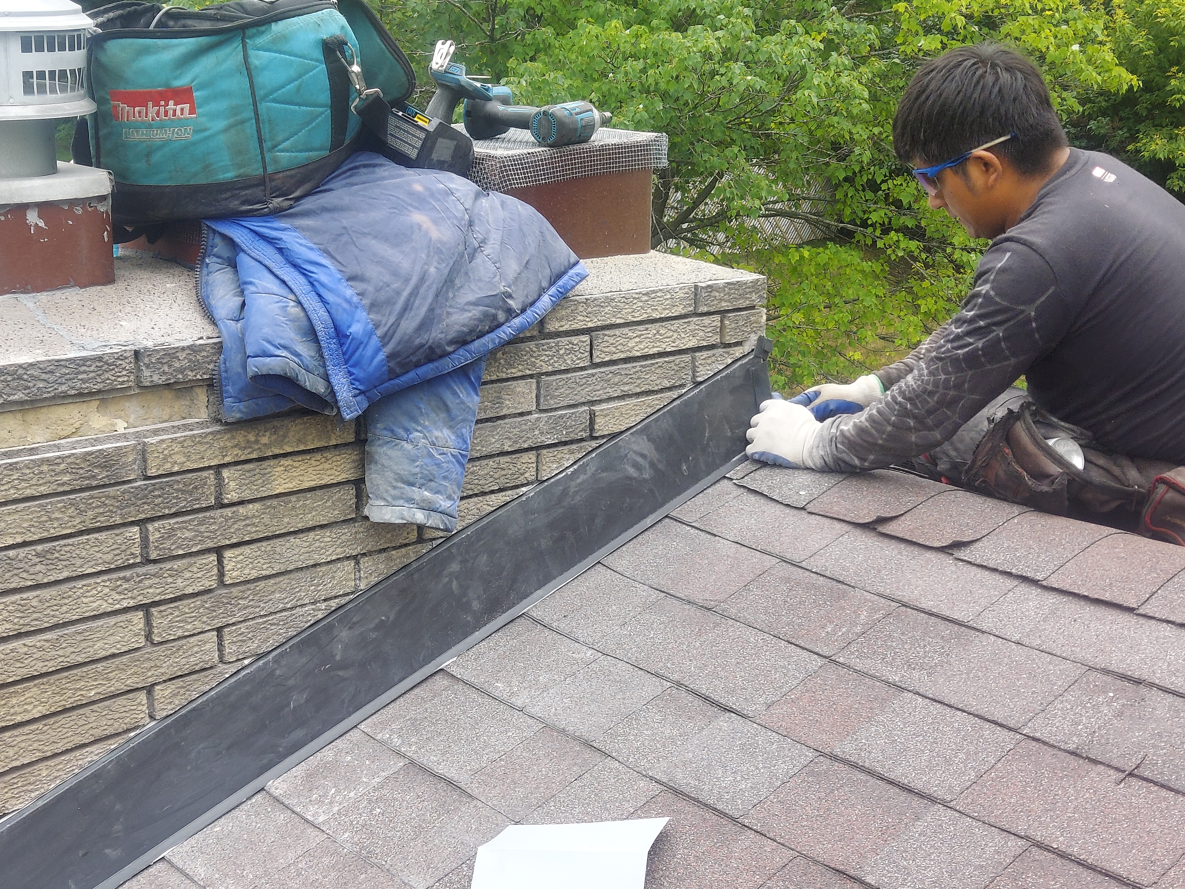 Storm Master tech installing chimney flashing during a Minnetonka retail roof repair.