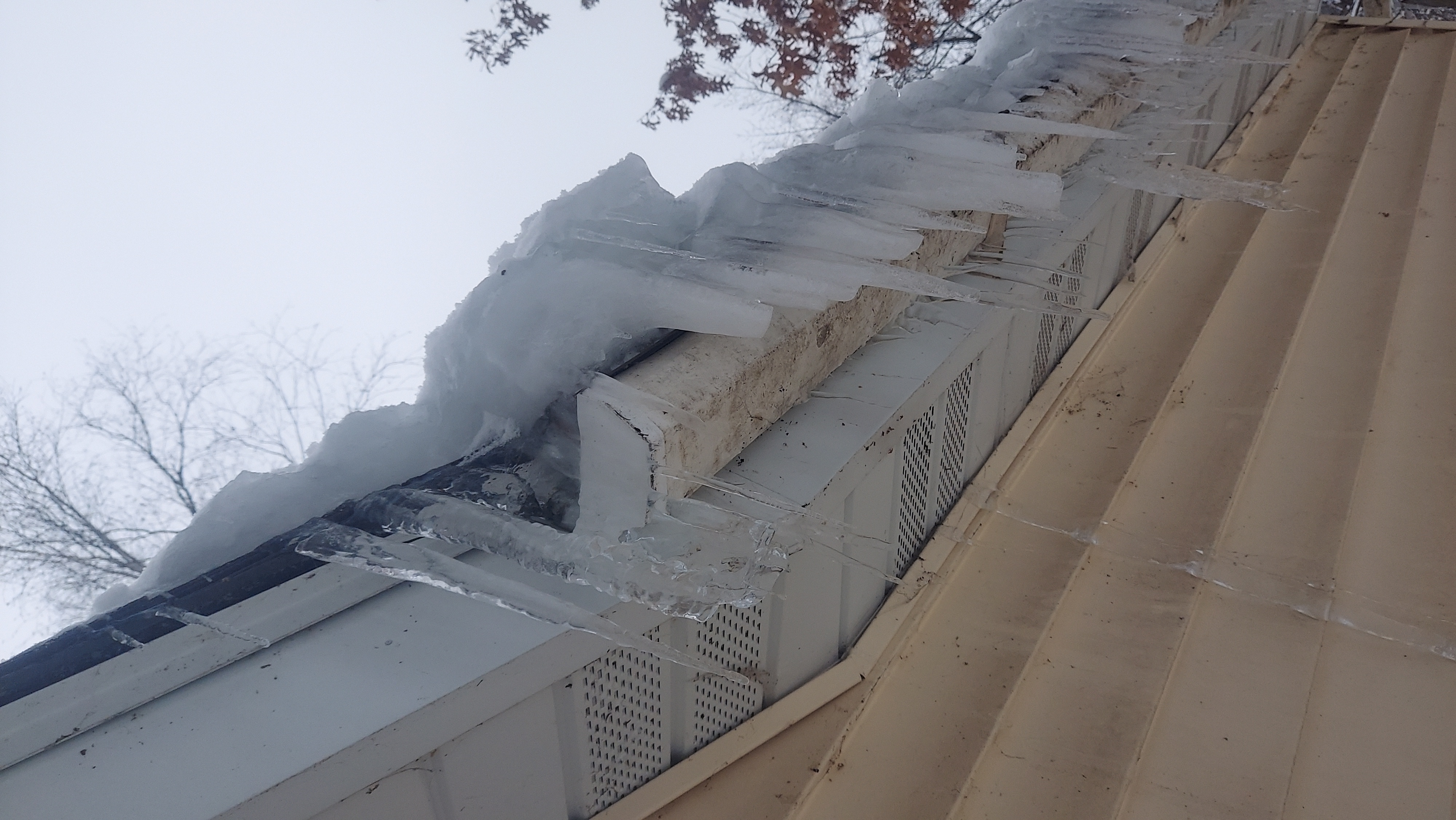 Ice overflowing gutter with icicles on Twin Cities home eaves