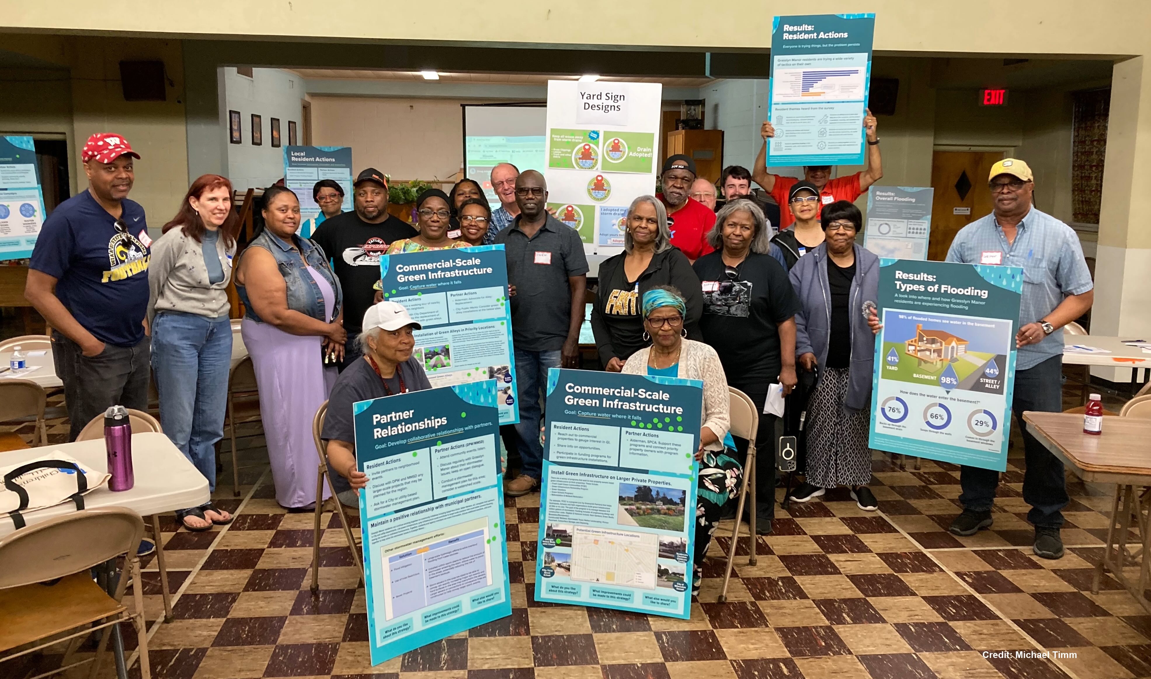 Members of the Building the Ark residential committee pose for a group photos with information boards illustrating results of the neighborhood survey