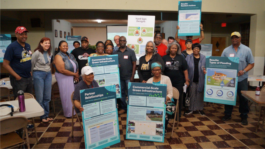 Over 20 community members attended a community meeting in 2024 to learn and dicuss the neighborhood flooding survey results shown on the poster boards held by attendees.