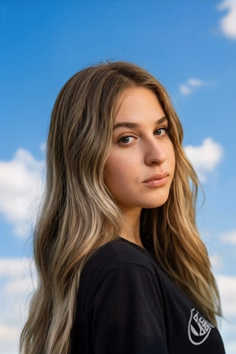 Taylor Sierra with long hair in a black top against blue sky