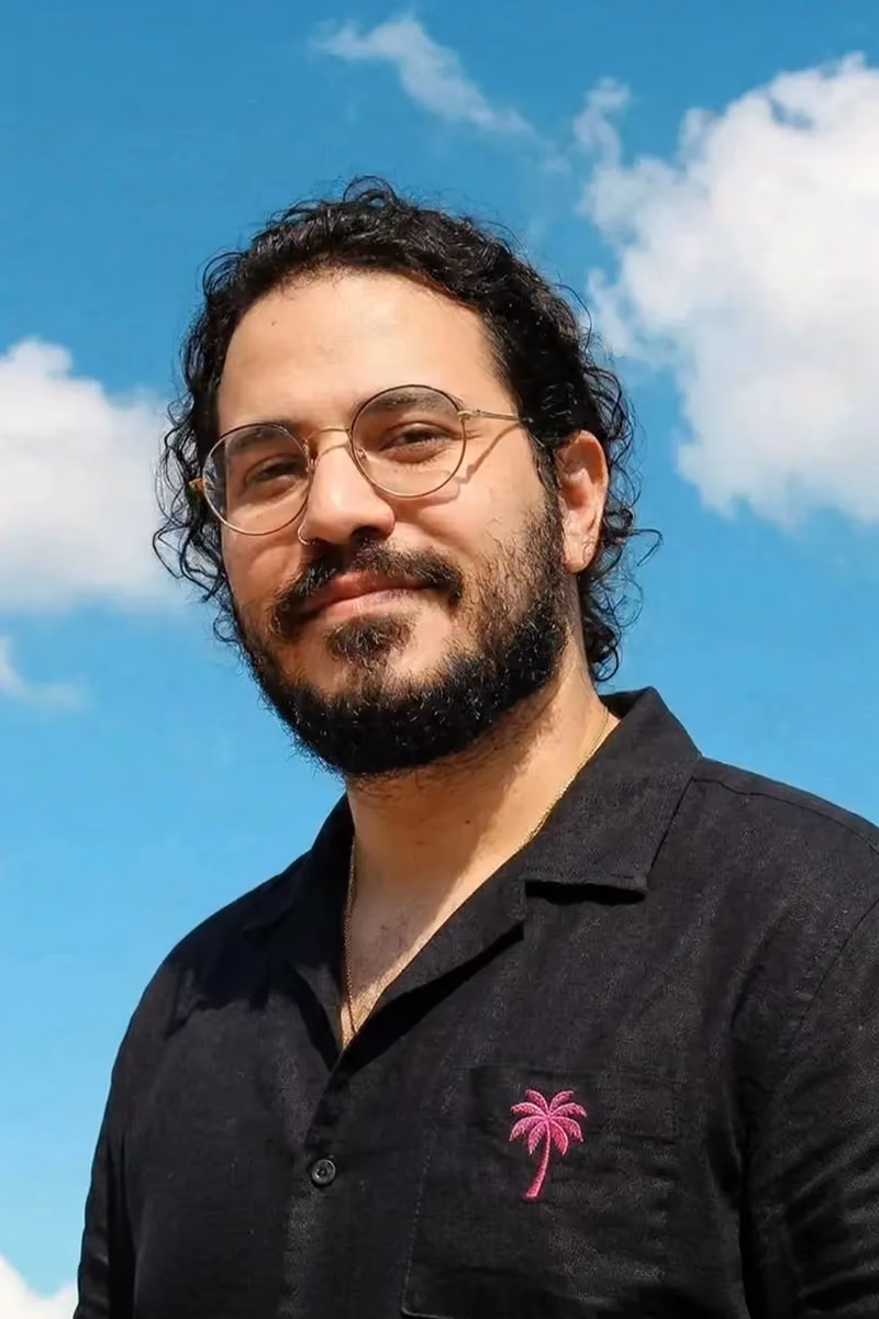 Vinni Larrubia smiling in glasses and a black shirt against blue sky