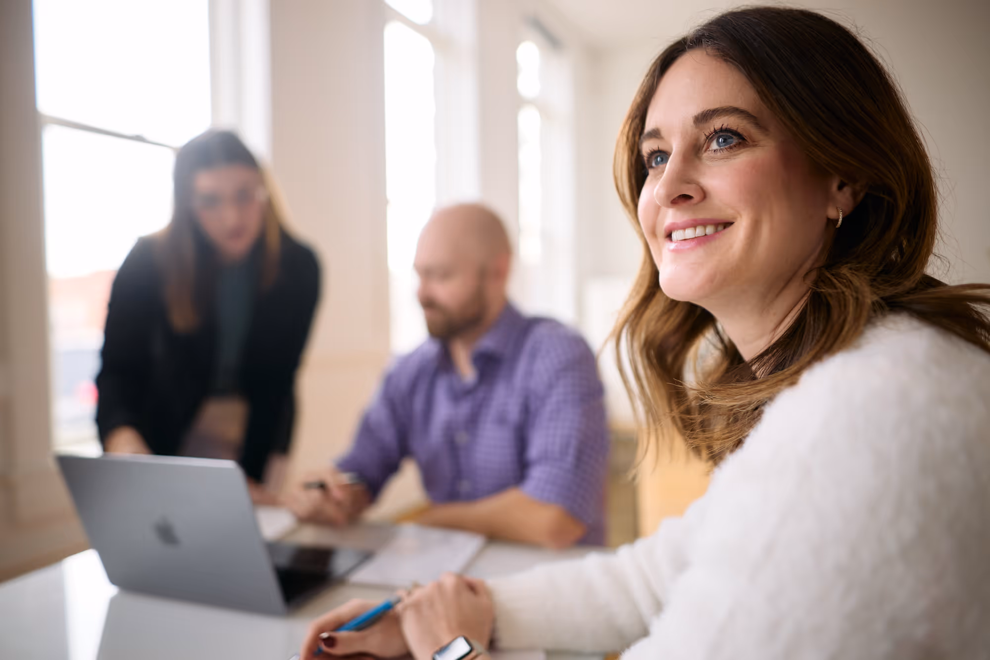 Three team members sitting at a desk together going through data reports