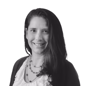 Black and white portrait of a smiling woman with long dark hair wearing a necklace and dark top.
