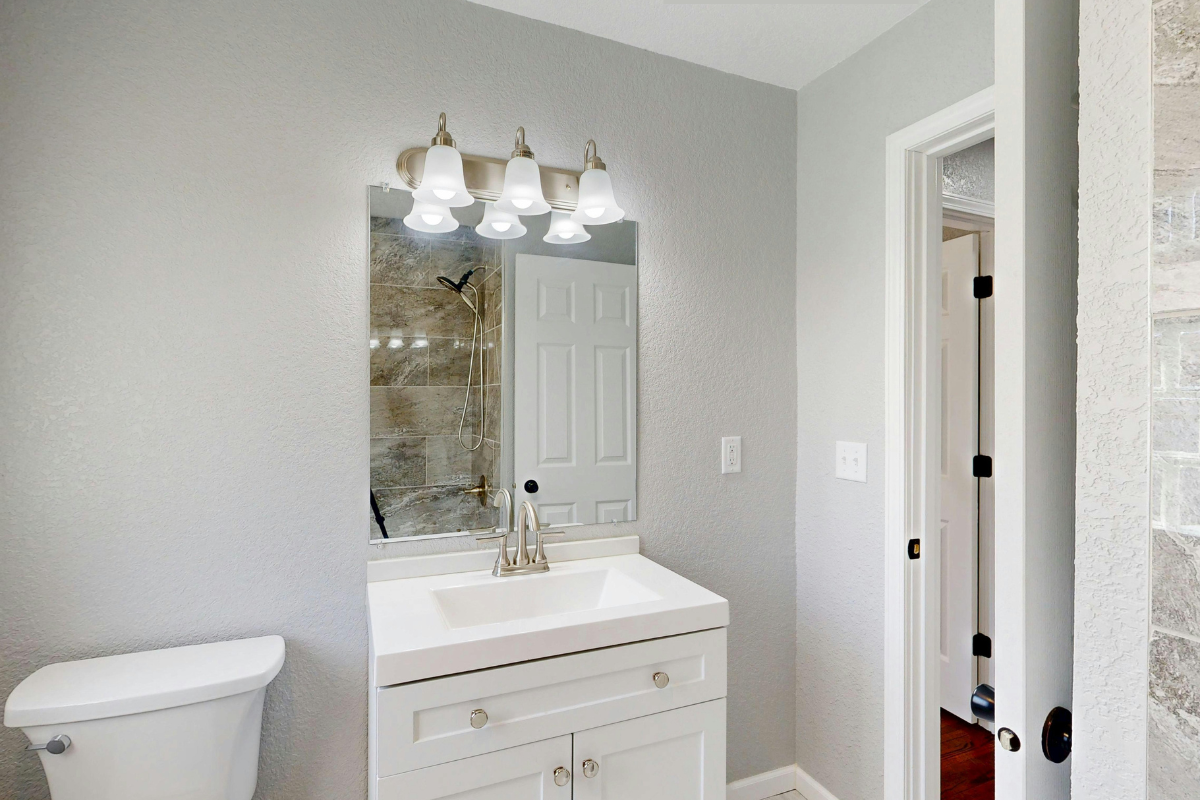 Bathroom with Mixing Metals of a Silver Faucet & Vanity Knobs and Golden Vanity Lights