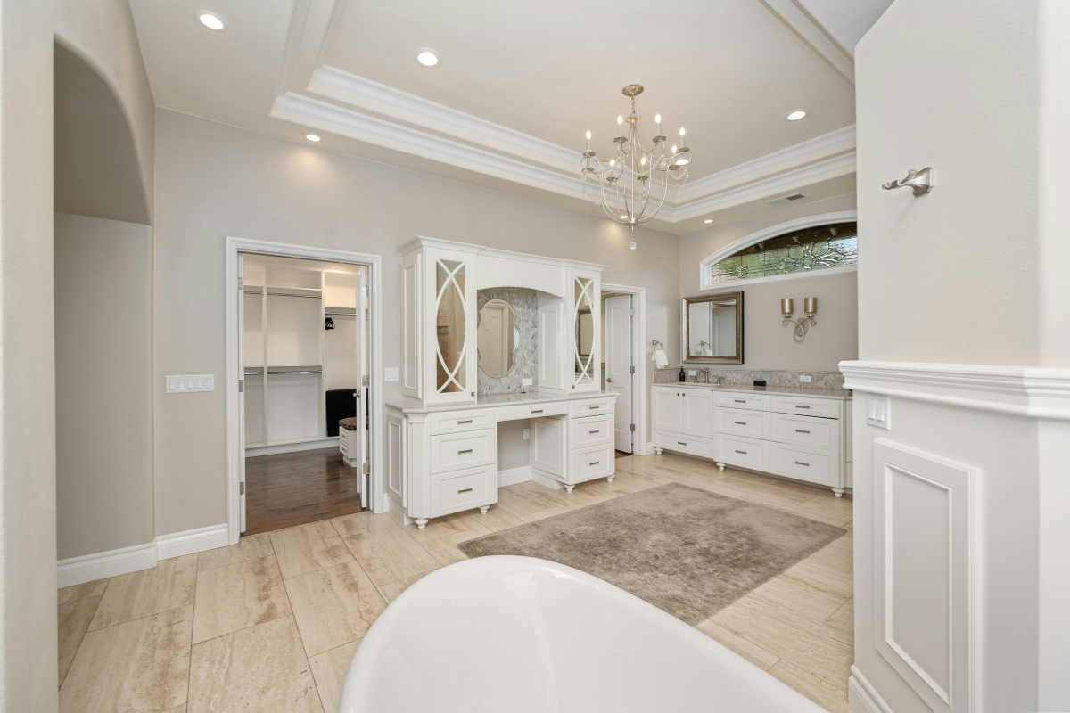 luxury primary bathroom with overhead lighting and a Chandelier