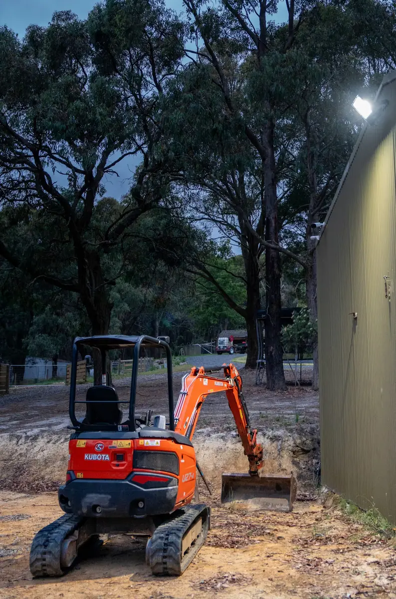 Mini excavator beside a farm shed at dusk