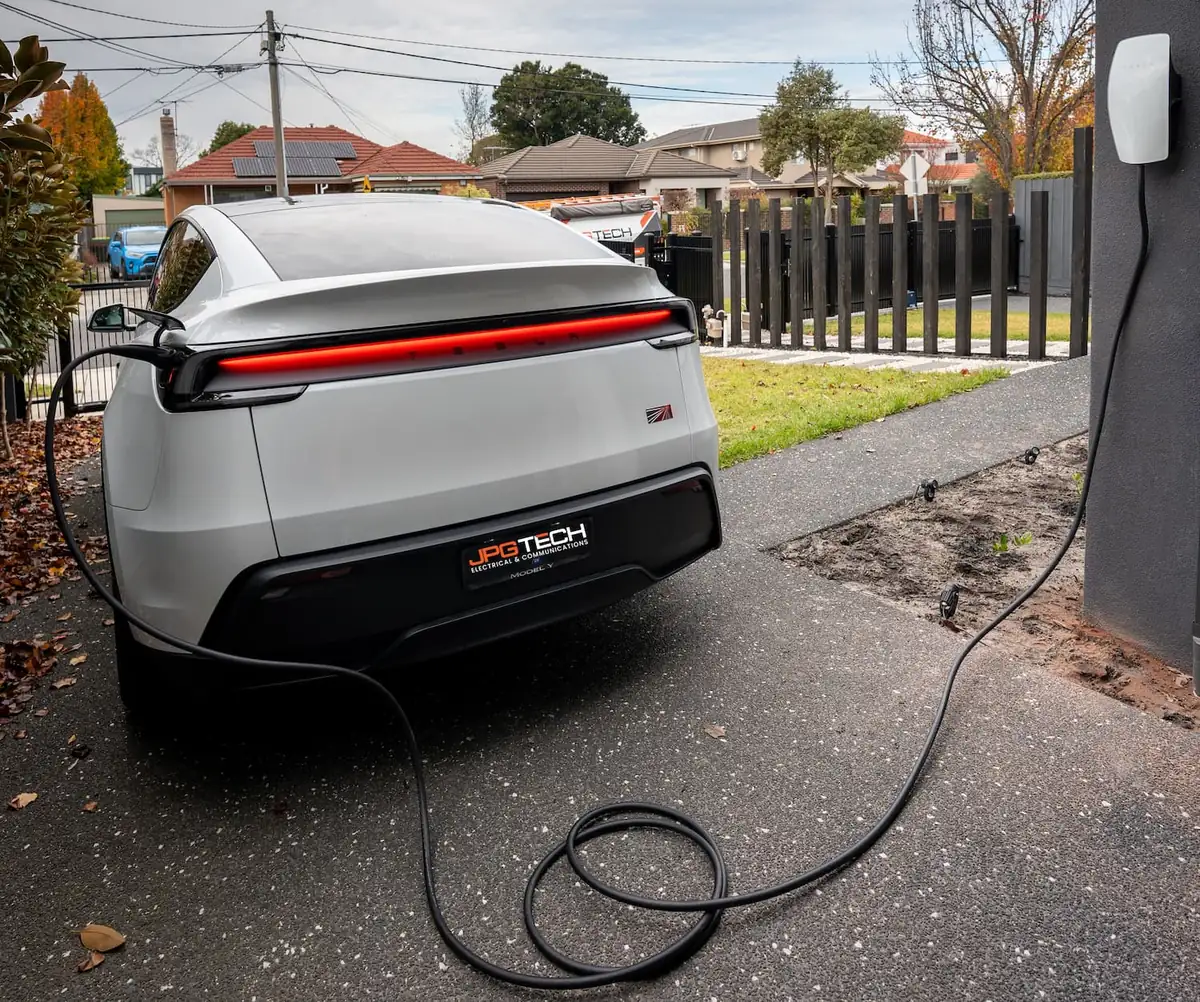 Tesla Model Y plugged into a wall connector on a Bentleigh driveway