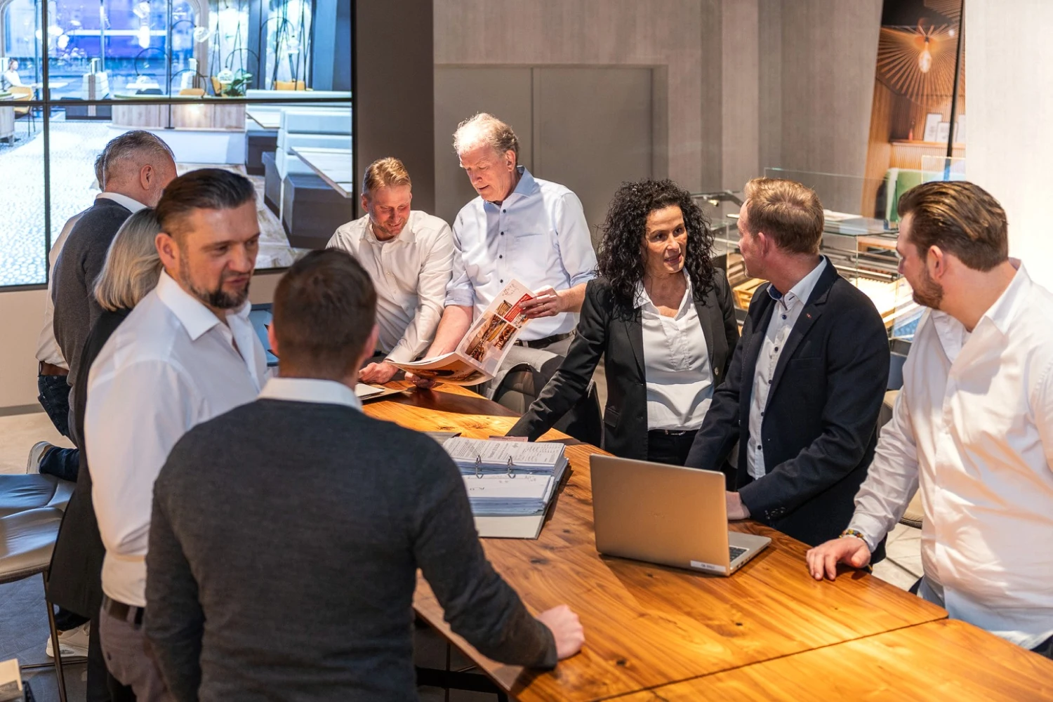Große Gruppe von Menschen winkt in die Kamera vor drei weißen Lieferwagen mit KÖRTE-Logo auf einem Parkplatz.