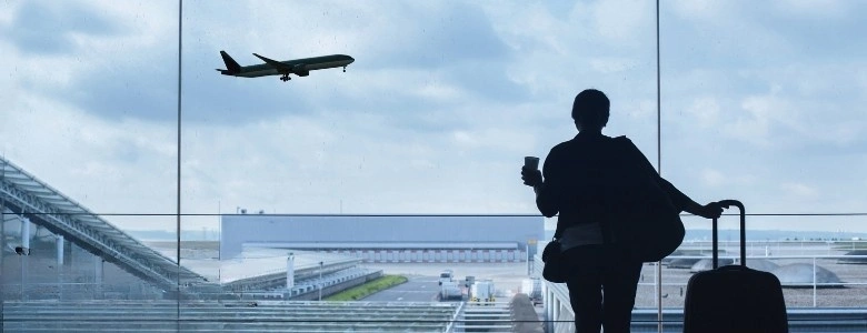 Traveller at Dubai airport watching an aeroplane before a long-haul flight, representing travel recovery and jet lag wellness.