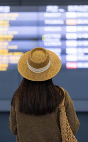 Traveller checking departure board at Dubai airport before flying, illustrating jet lag recovery and travel wellness.
