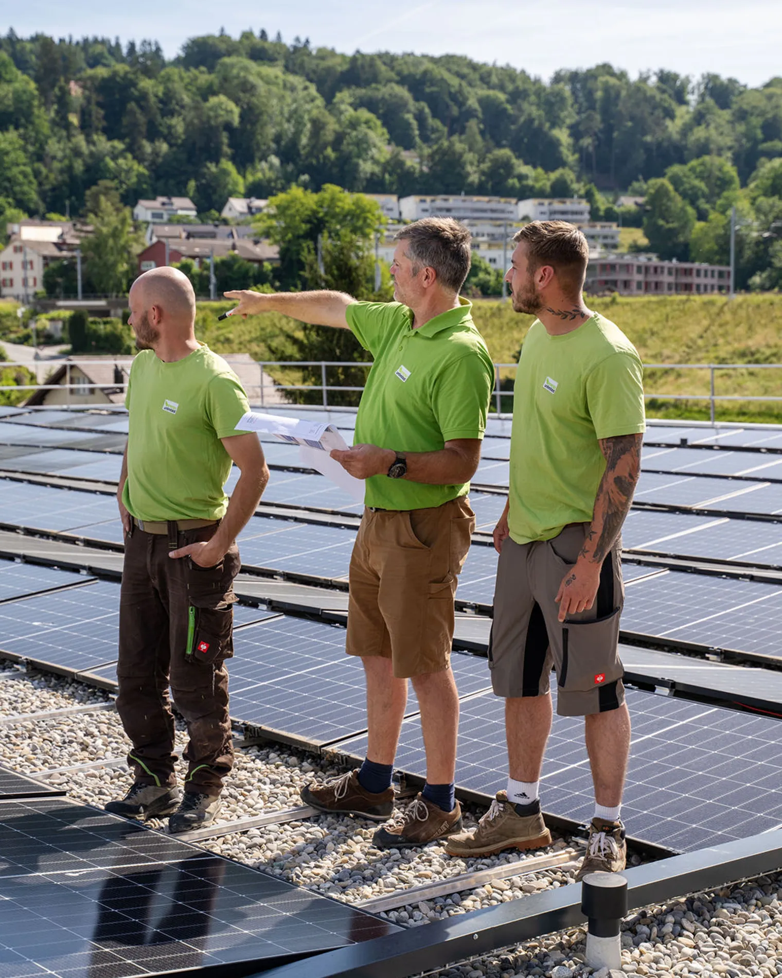 Planer und Monteure von energy unlimited AG besprechen Plan auf einem Industriedach mit Solaranlage.