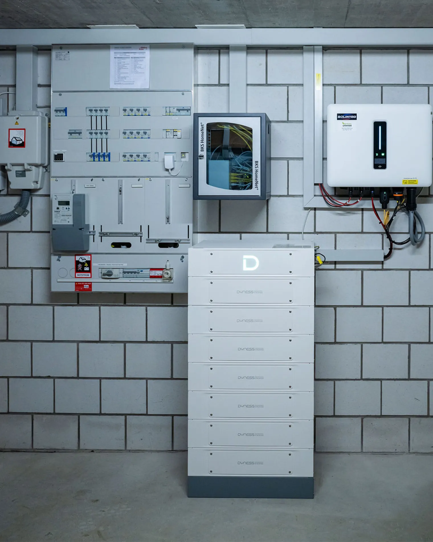 Draufsicht auf ein modernes Flachdachgebäude mit einer großflächigen Photovoltaikanlage. Die Solarpaneele sind in mehreren Reihen angeordnet, mit begrünten Flächen dazwischen.