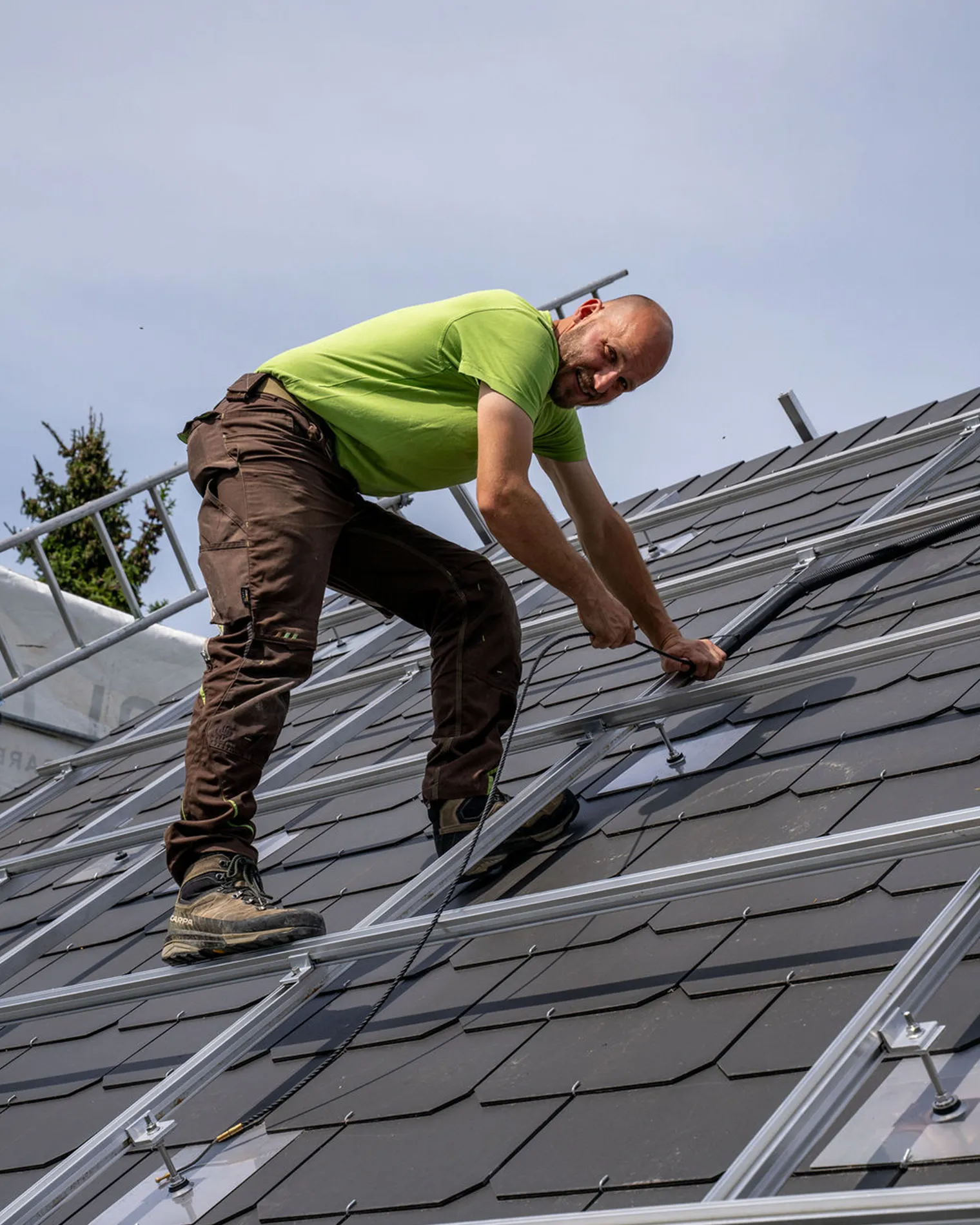 Mitarbeiter von energy unlimited AG montiert auf einem Steildach eine Photovoltaikanlage