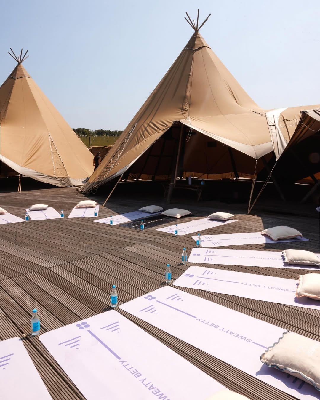 Yoga mats and canvas tents arranged outdoors for a morning Sweaty Betty retreat session.
