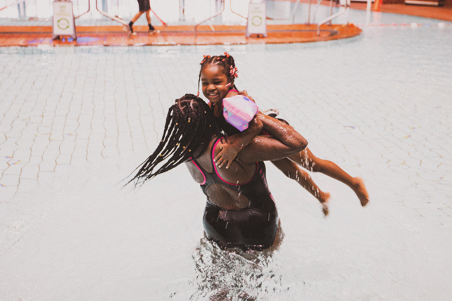 Mother joyfully lifting her daughter out of the water during Speedo Swim United swim class.