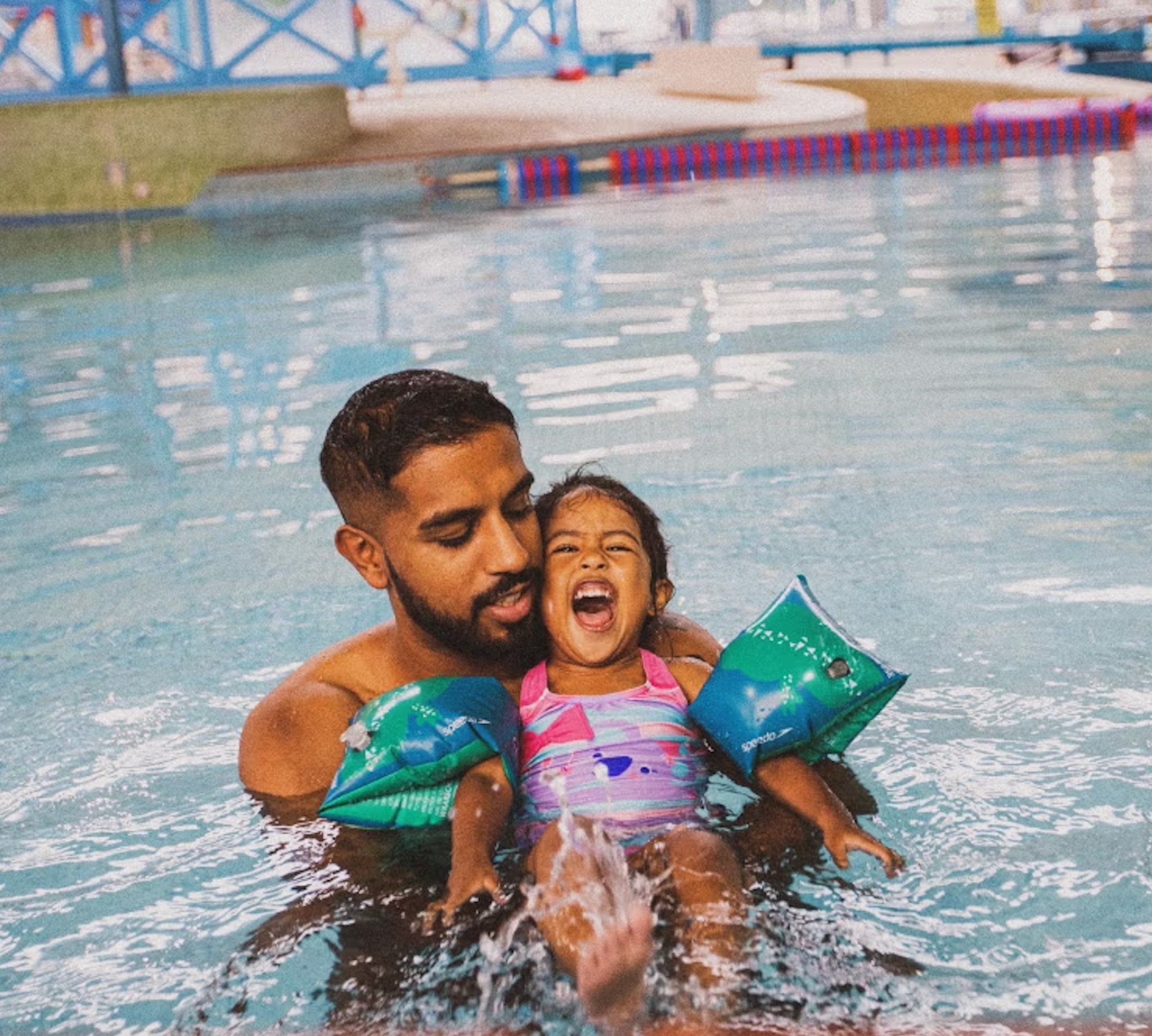 Father teaching his young daughter to swim during Speedo Swim United family lesson.