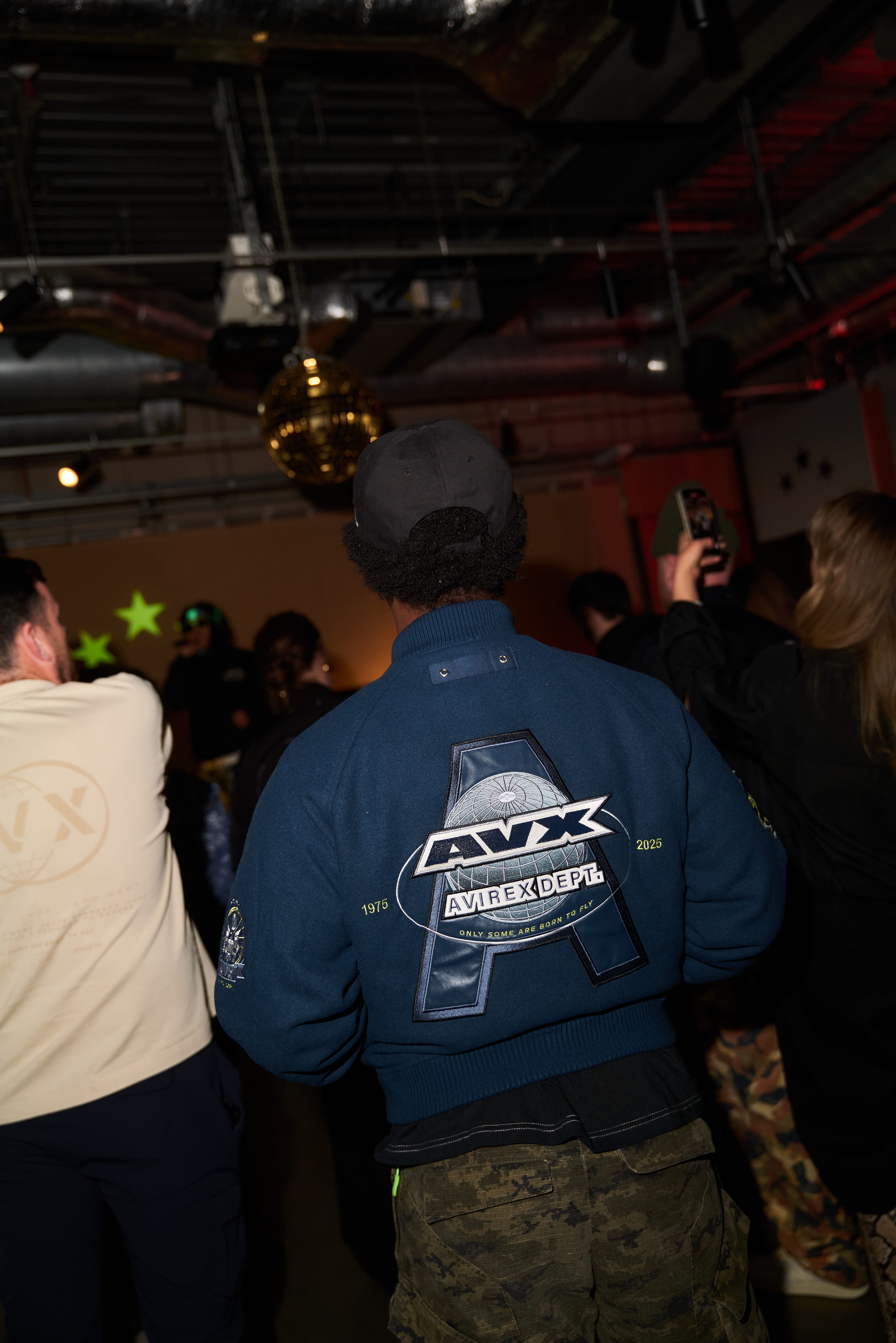 Back view of attendee wearing navy jacket featuring large AVX logo embroidery at AVX Live event.