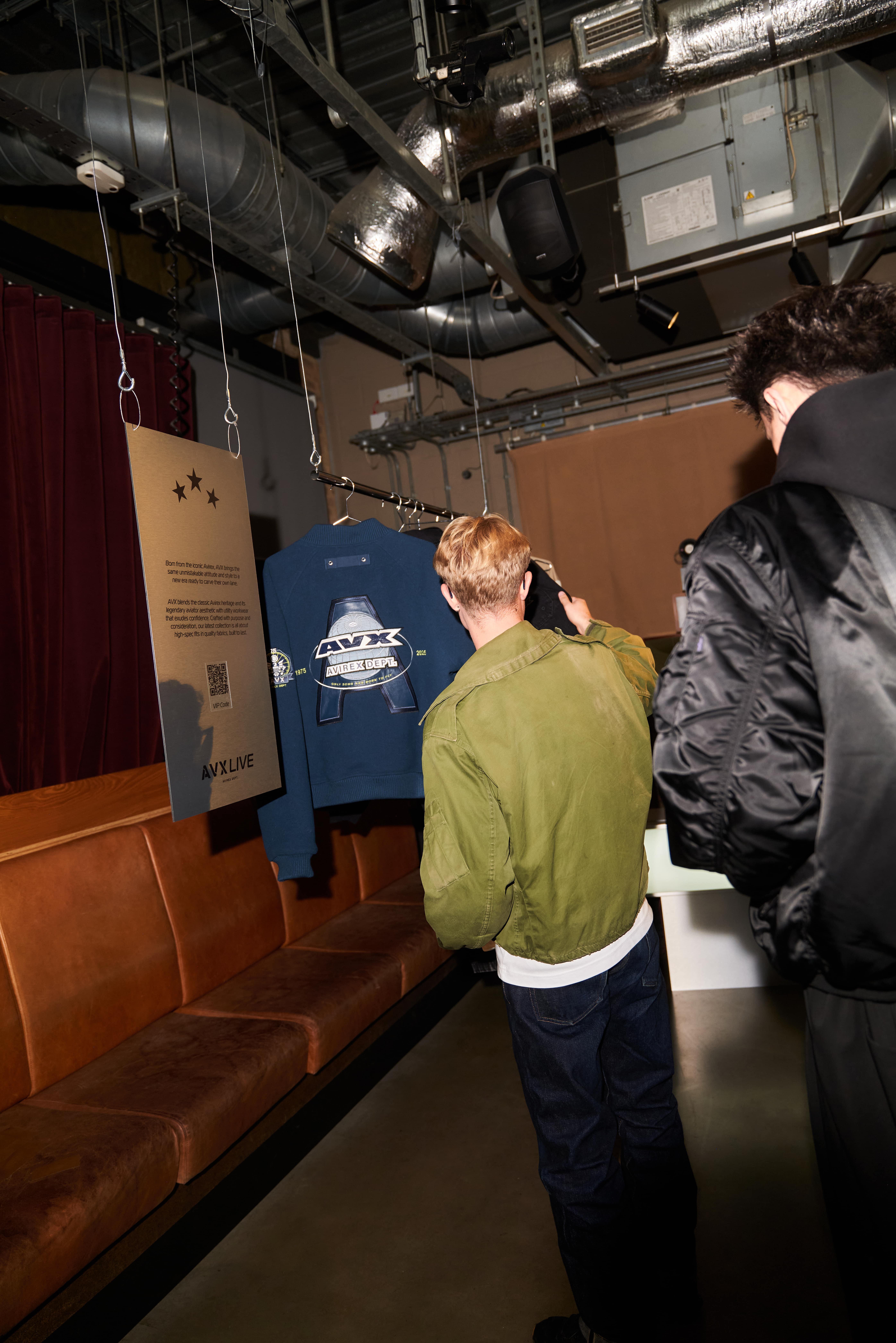 Guest examining AVX branded hoodie at merchandise section during AVX Live event.