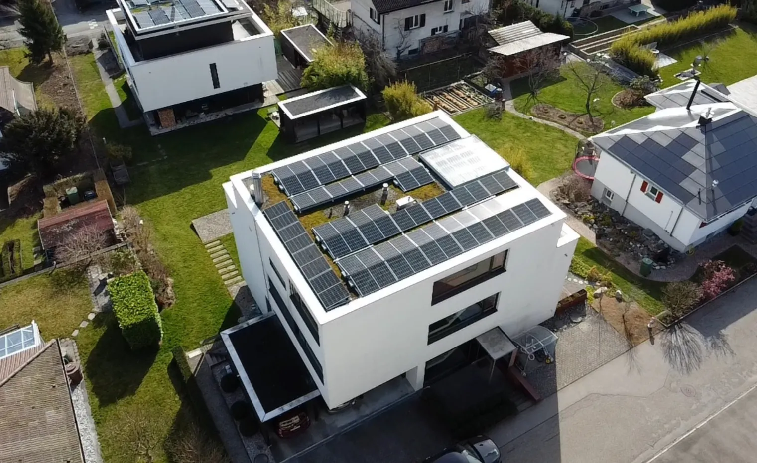 Modernes Wohnhaus mit grosser Photovoltaikanlage auf dem Flachdach – Symbol für die zunehmende Solarstromproduktion und die Marktöffnung im Schweizer Strommarkt ab 2026