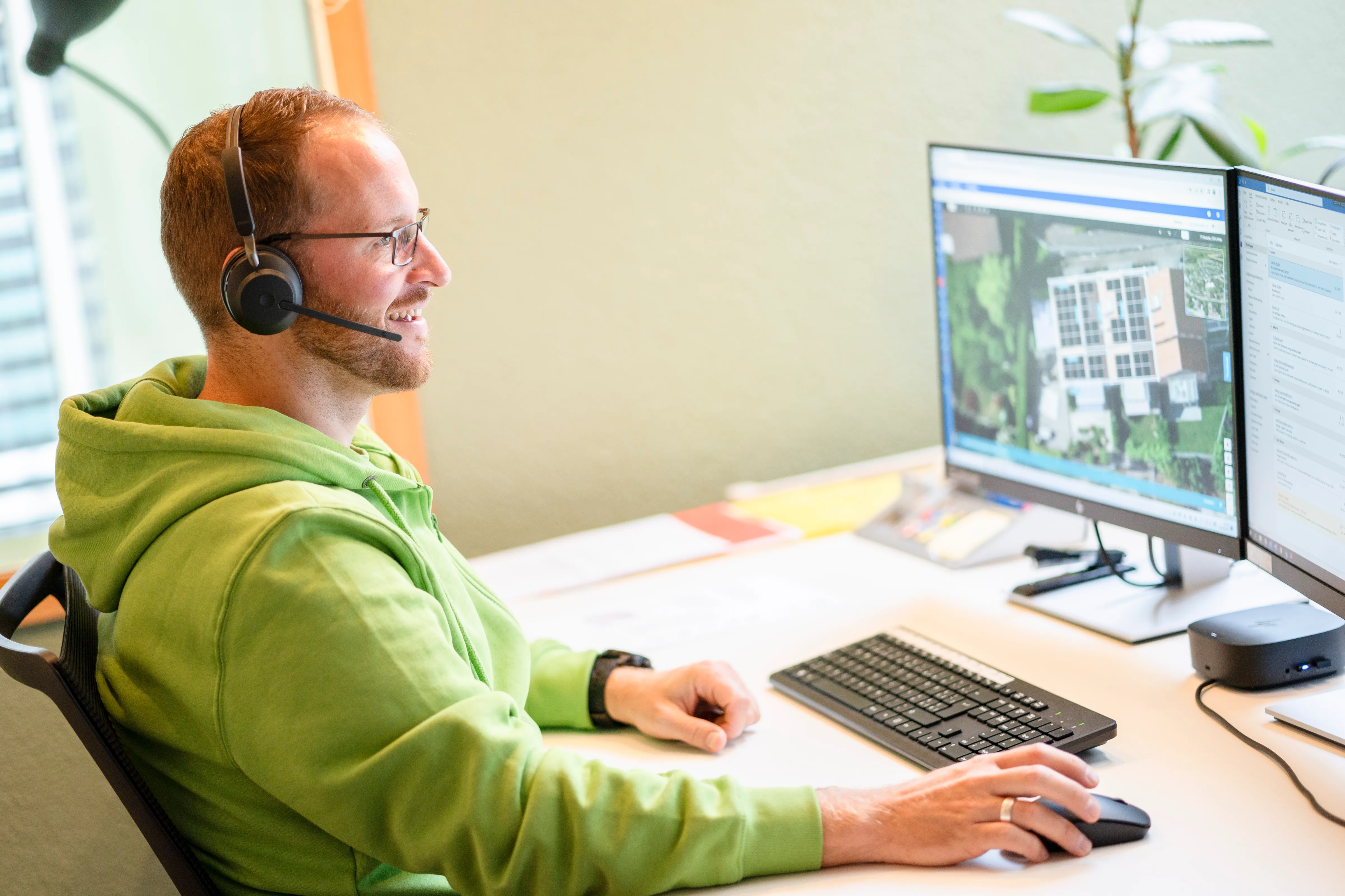 Mitarbeiter von energy unlimited mit Headset arbeitet am Computer und betrachtet Solaranlagen auf dem Bildschirm.
