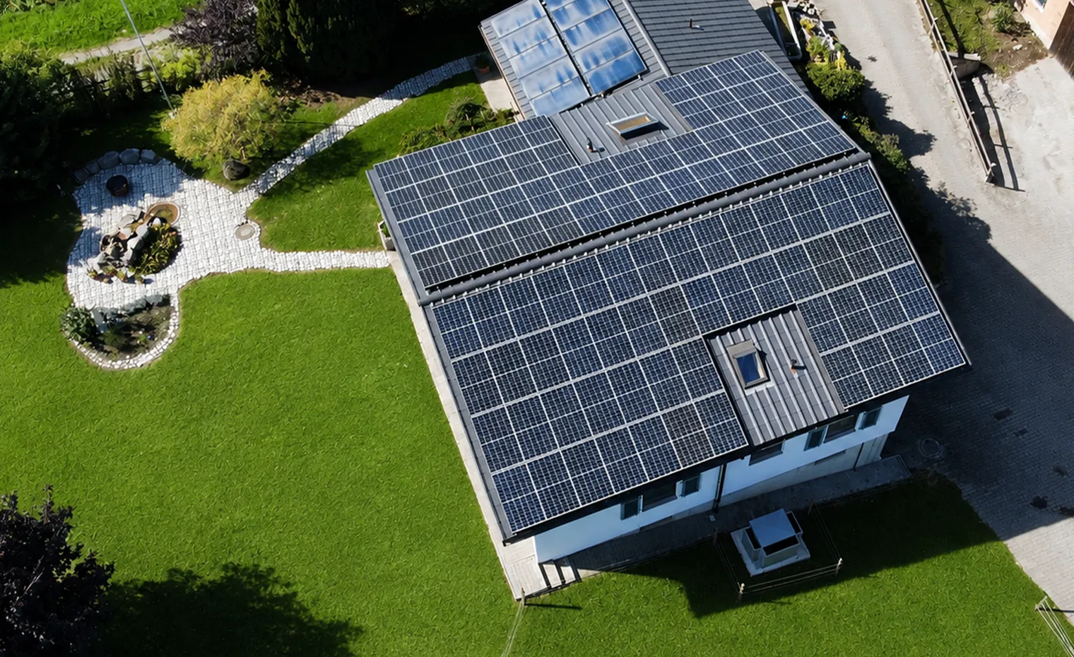 Luftaufnahme eines Einfamilienhauses mit grosser Photovoltaikanlage auf dem Dach – Beispiel für Eigenstromnutzung im Zusammenhang mit der Abschaffung des Eigenmietwerts in der Schweiz