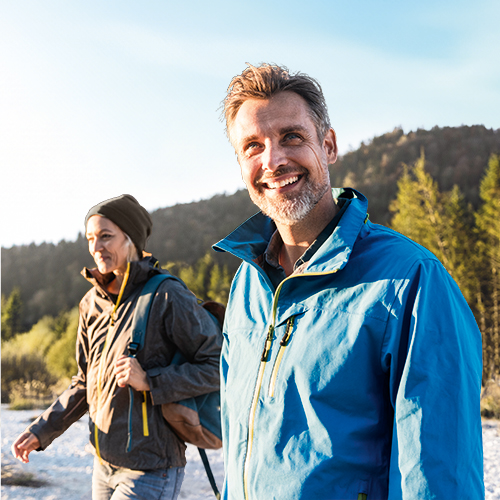 Een lachend paar wandelt ondanks hun osteoartritis pijnvrij in de natuur.
