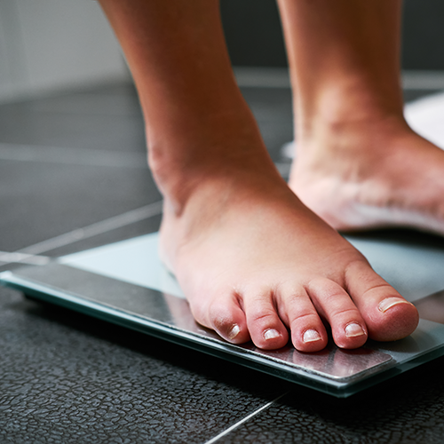 Voeten van een persoon die op een weegschaal staat.