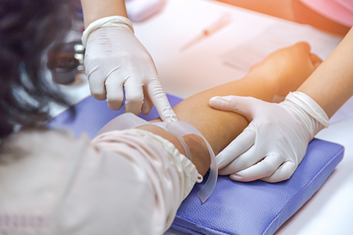 Een arts duidt bij een patiënt aan waar de aders lopen om bloed te nemen.