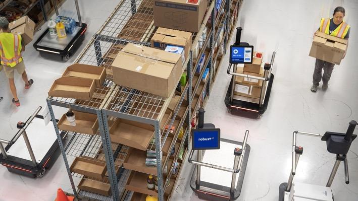 Busy warehouse with humans, stock and autonomous robots moving around