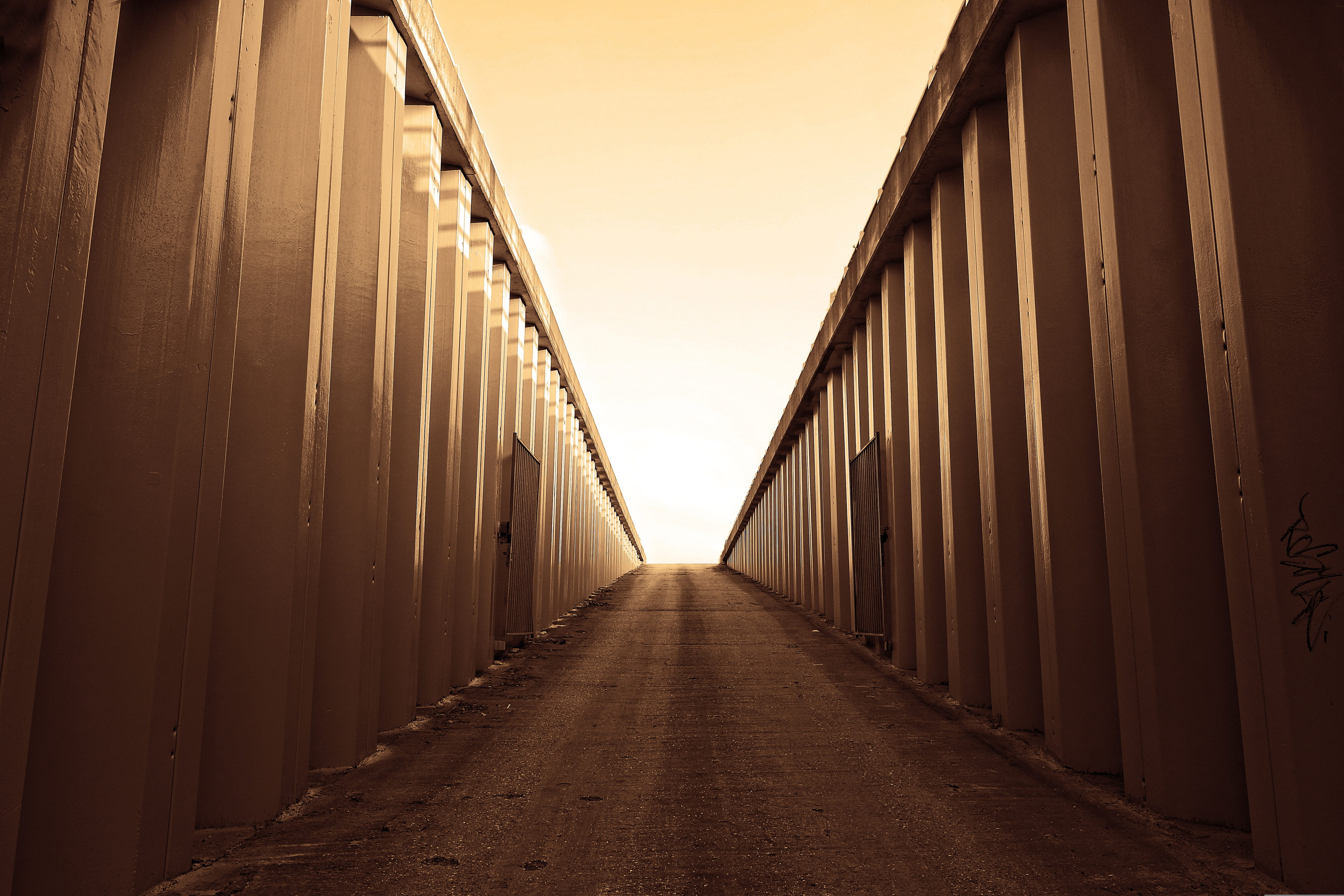 A long corridor of warehouse storage units stretching into the distance, representing the critical warehouse investment decisions and operational planning challenges that cannot be deferred as budget season and peak season preparation converge.