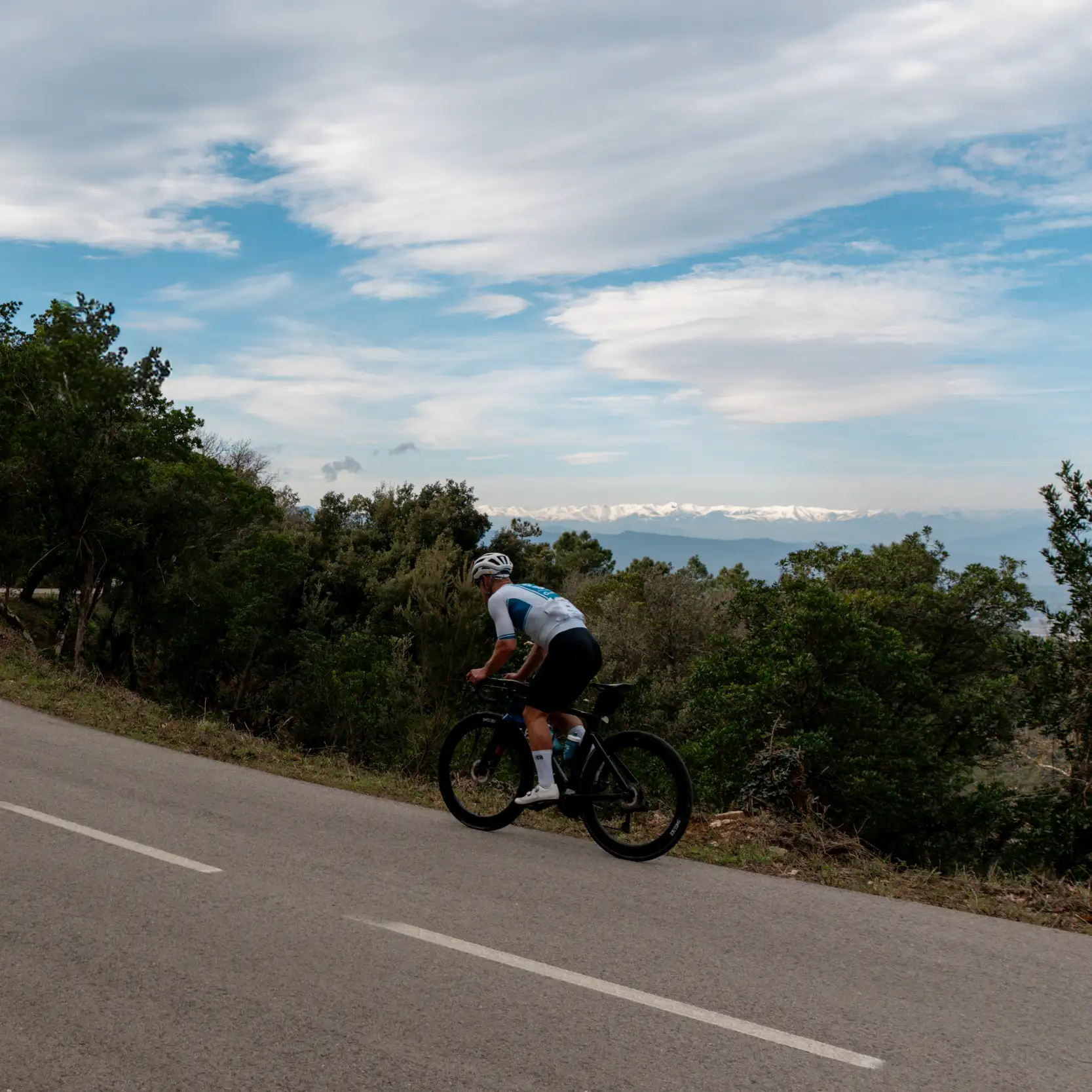 Ascension à vélo de route face aux sommets enneigés des Pyrénées, panorama d'un stage cyclisme en Catalogne