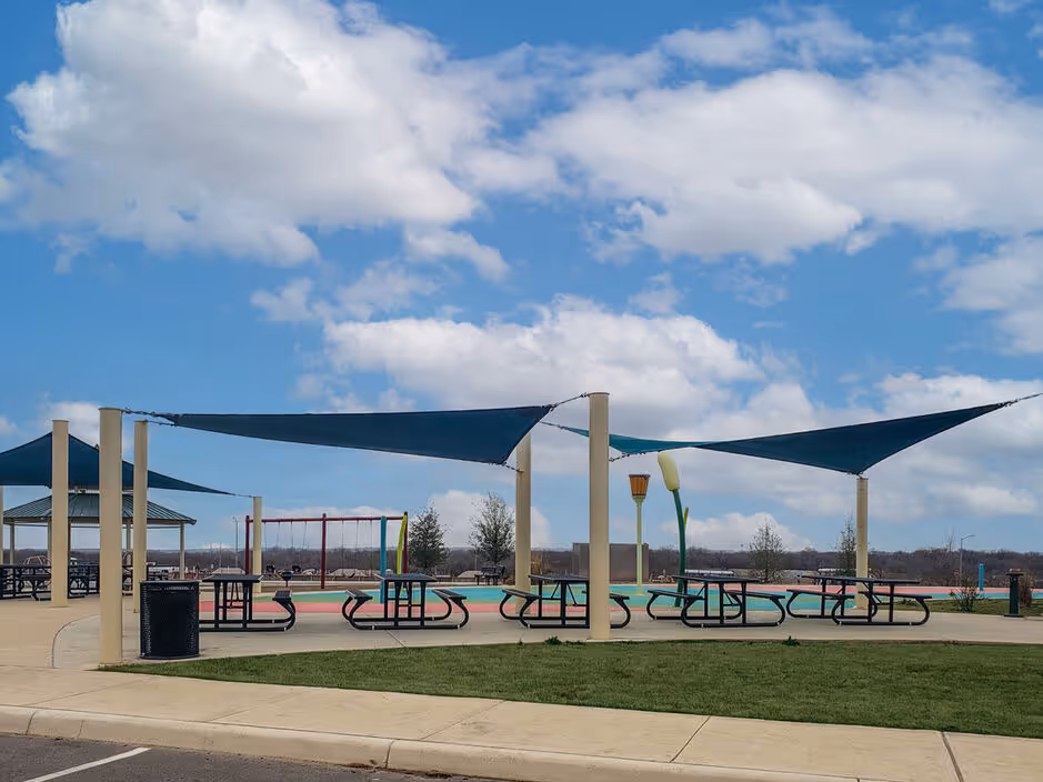 Community park area with picnic tables shaded by large blue canopies, offering outdoor gathering space at Enclave at Medina in Von Ormy, TX.