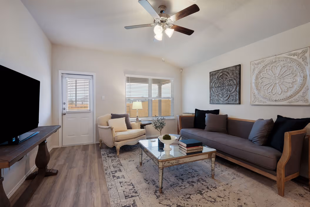 Cozy living room with a sofa, armchair, coffee table, and ceiling fan, typical of homes at Enclave at Medina in Von Ormy, TX.