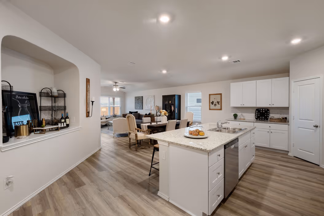Expansive view of the open-concept living, dining, and kitchen areas with wood-look flooring, designed for modern living at Enclave at Medina in Von Ormy, TX.